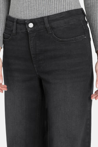 Jean décontracté noir de denim de MAC, coupe courte avec vue sur la ceinture et un pull gris.