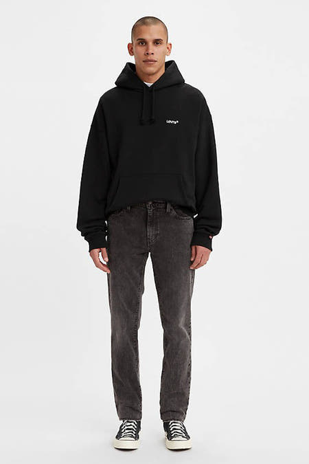 Donkergrijze slim fit jeans van Levi's® met gewassen denimlook, gedragen met zwarte hoodie en sneakers, front view