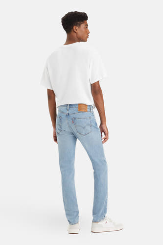 Slim fit jeans van lichtblauw denim van Levi's, met witte t-shirt en witte schoenen.