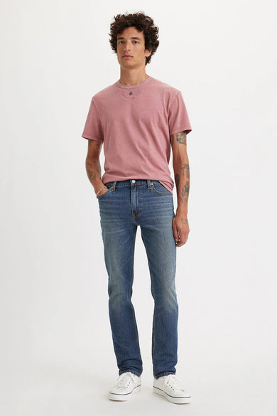 Mid blue slim-fit jeans van Levi's® met lichte was, gedragen met roze t-shirt en witte sneakers, front view