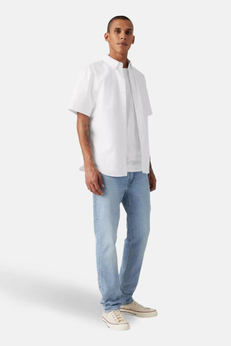 Jean slim fit en denim bleu clair de Levi's, avec un T-shirt blanc et une chemise blanche.