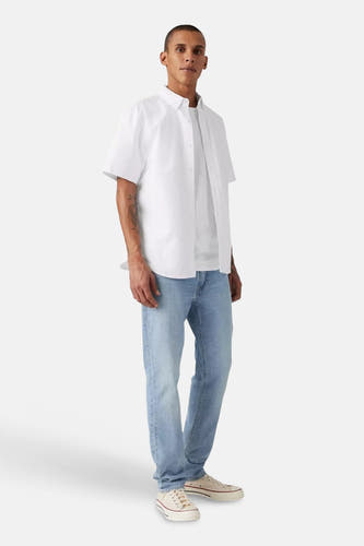 Slim fit jeans van Levi's®, in lichtblauw denim, gecombineerd met witte sneakers en een wit overhemd.