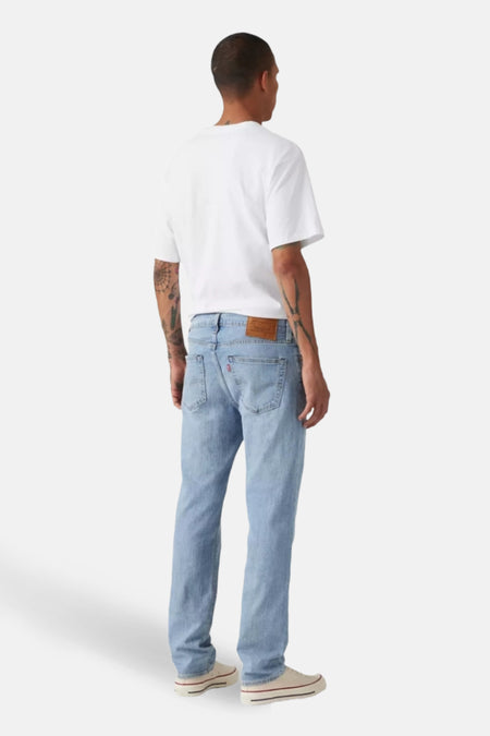 Slim fit jeans van lichtblauw denim van Levi's®, gezien van achteren, gecombineerd met een wit T-shirt en crèmekleurige schoenen.