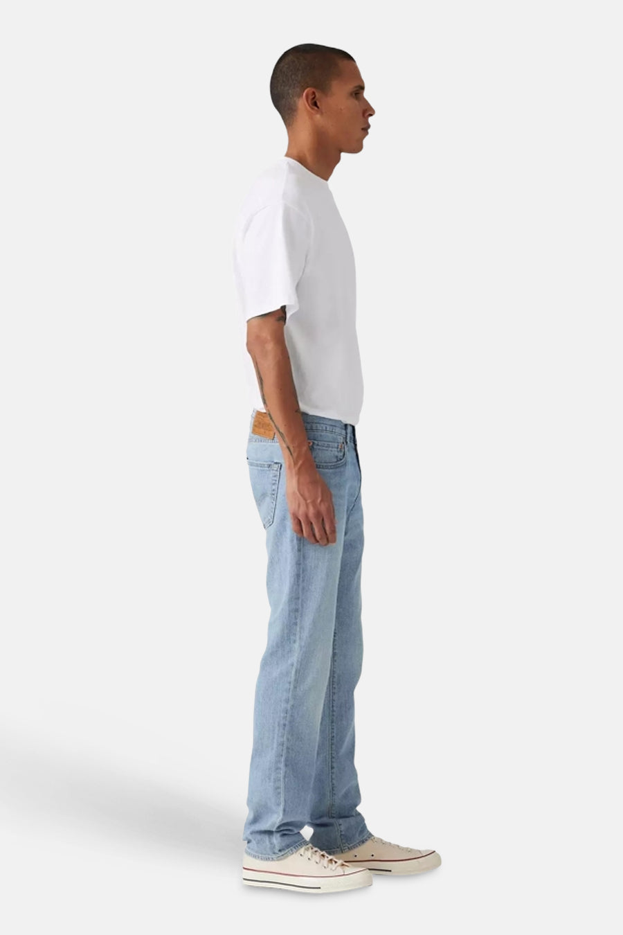 Lichtblauwe slim jeans van Levi's, gezien vanaf de zijkant, gecombineerd met een wit T-shirt en crèmekleurige sneakers.
