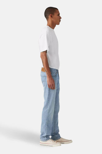 Jean slim de denim bleu clair de Levi's, vu de du côté, associé à un T-shirt blanc et des baskets blanches.