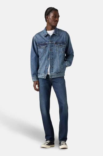 Slim fit jeans van donkerblauw denim van Levi's, gecombineerd met een spijkerjas en zwarte sneakers.
