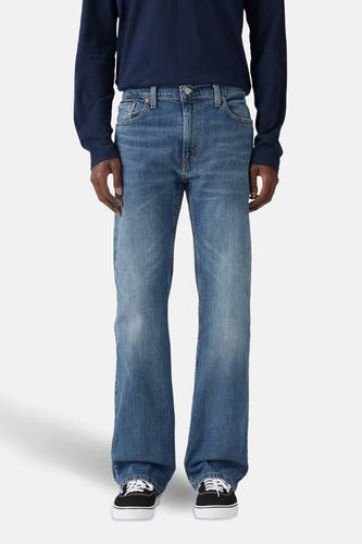 Bootcut jeans van blauw denim van Levi's, gedragen met een donkerblauw shirt en zwarte sneakers.