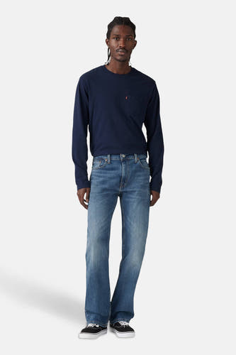 Blauwe denim bootcut jeans van Levi's, gedragen met een donkerblauw shirt met lange mouwen en zwarte sneakers.