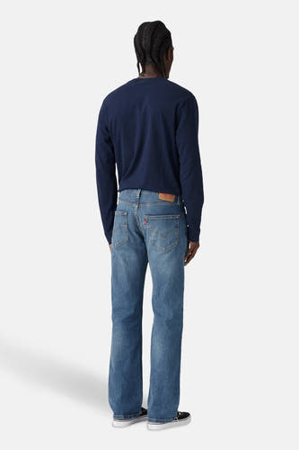 Blauwe denim bootcut jeans van Levi's, gezien van achteren, met donkerblauw shirt en zwarte schoenen.