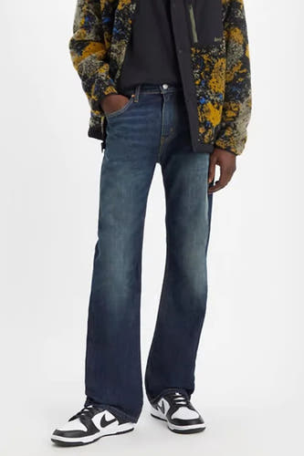 Bootcut jeans van denim door Levi's®, gecombineerd met een fleece jas met print en witte sneakers.
