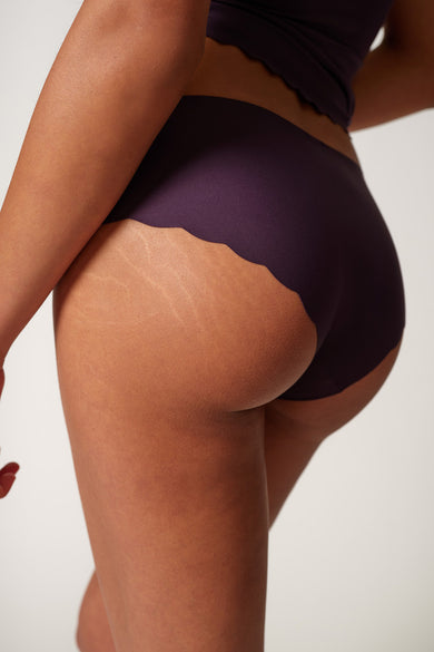 Paarse slip van SKINY, met een golvende rand, gedragen door een model, achterkant zichtbaar.
