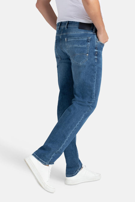 Middenblauwe rechte jeans van MAC met subtiele textuur, gecombineerd met een wit shirt en witte sneakers.