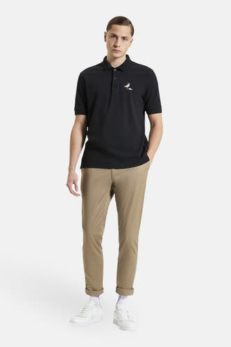 Zwarte polo met korte mouwen van Ben Sherman, met een geborduurde vogel, gecombineerd met kaki broek en witte sneakers.
