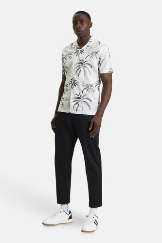 Wit overhemd met korte mouwen van BEN SHERMAN, met een palmbomenprint en gecombineerd met een zwarte broek en witte sneakers.
