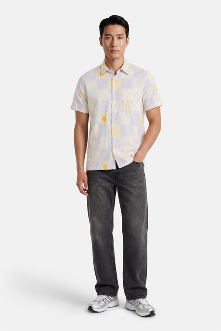 Multicolor hemd met korte mouwen van BEN SHERMAN, met geblokt patroon van zonnen en golven, gedragen met donkere jeans en zilveren sneakers.