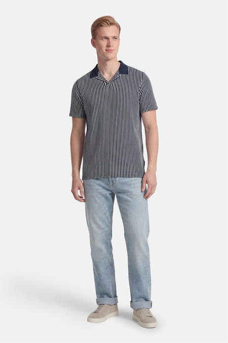 Polo rayée bleue à manches courtes de BEN SHERMAN, associée à un jean bleu clair et des baskets en daim.