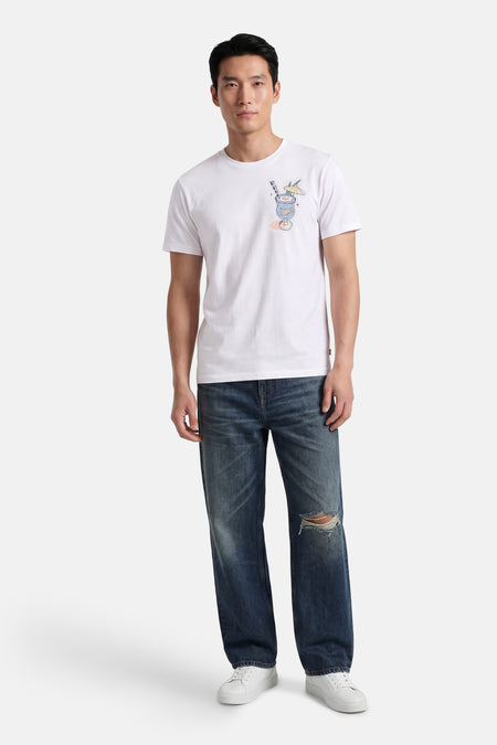 Wit T-shirt van BEN SHERMAN met cocktailglas-print met vis, rietje en parasol, gedragen door een man met distressed spijkerbroek en witte sneakers.