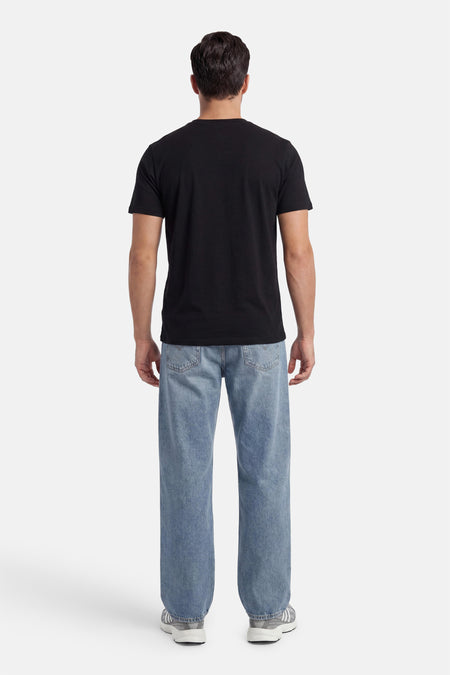 Zwart T-shirt met korte mouwen van BEN SHERMAN, getoond in achteraanzicht, gedragen met blauwe jeans en grijze sneakers.