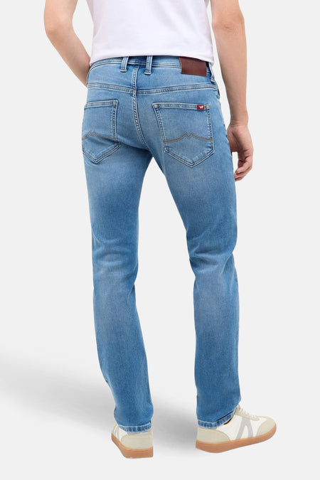 Jeans slim van lichtblauwe denim van MUSTANG, met zichtbare achterzakken en witte sneakers.
