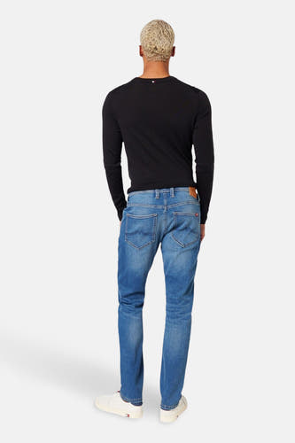 Blauwe slim-fit jeans van MUSTANG, gezien van achteren, gecombineerd met een zwart shirt met lange mouwen en witte schoenen.
