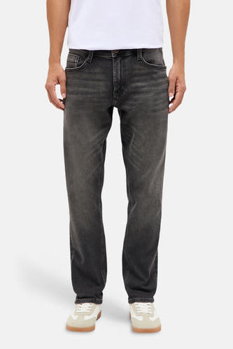 Jean slim gris foncé de Mustang, aspect denim délavé, vue de face, le modèle porte un t-shirt blanc et des baskets beige