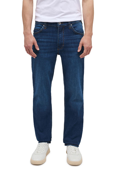 Jean droit bleu marine de MUSTANG, avec un lavage subtil et porté avec des baskets blanches et une chemise blanche.