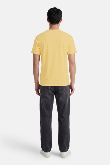 Geel T-shirt met fijne textuur van BEN SHERMAN, achteraanzicht, gecombineerd met donkergrijze jeans en witte sneakers.