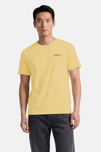 Geel T-shirt van BEN SHERMAN met discreet geborduurd logo, gedragen door een model met een donkere spijkerbroek.