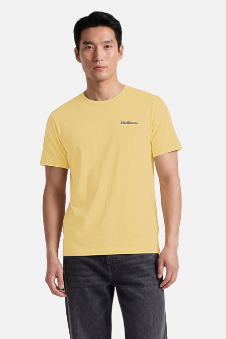 Geel T-shirt van BEN SHERMAN met discreet geborduurd logo, gedragen door een model met een donkere spijkerbroek.