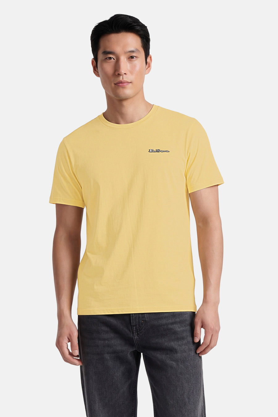 Geel T-shirt van BEN SHERMAN met discreet geborduurd logo, gedragen door een model met een donkere spijkerbroek.