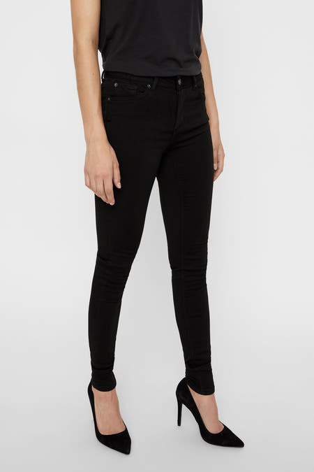 Jean skinny noir de VERO MODA, porté avec un haut noir et des baskets noires.