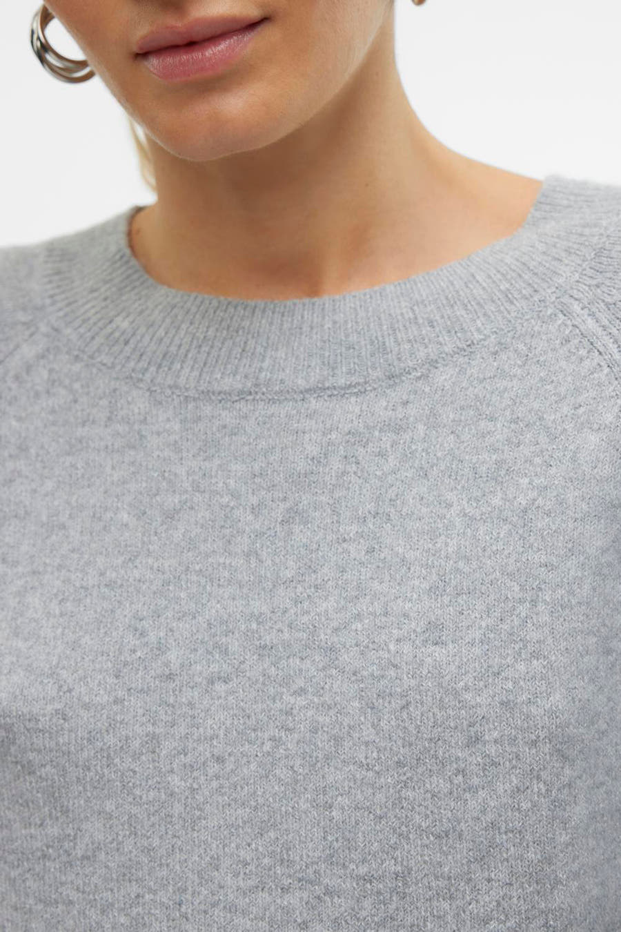 Grijze trui met ronde hals van VERO MODA, cropped close-up, met zilveren oorring.
