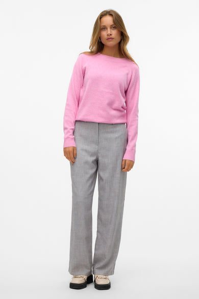 Roze trui met ronde hals van Vero Moda, gecombineerd met grijze pantalon en crèmekleurige schoenen met dikke zool.
