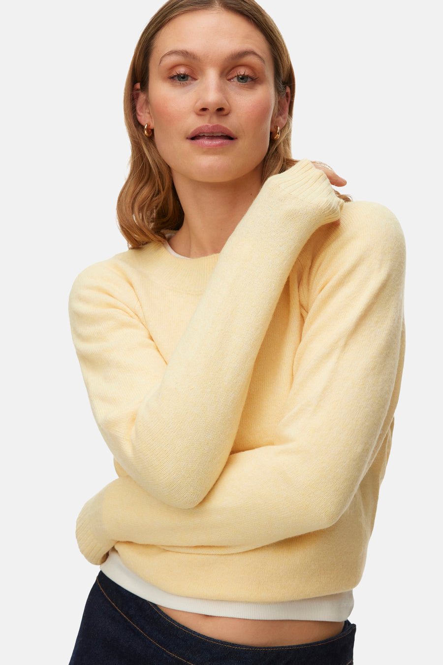 Gele trui met ronde hals van VERO MODA, met lange mouwen, gedragen met een donkere spijkerbroek.
