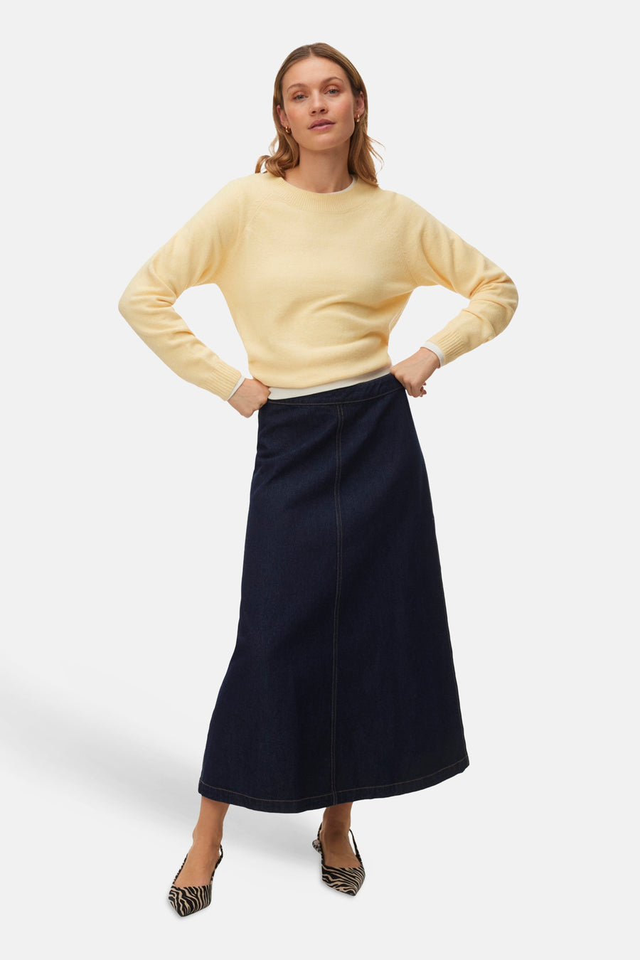 Gele trui met ronde hals van VERO MODA®, gecombineerd met een donkerblauwe denim rok en schoenen met zebraprint.
