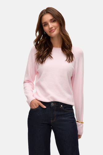 Blouse rose avec col rond de VERO MODA®, portée avec des jeans bleus foncés et des escarpins bordeaux.