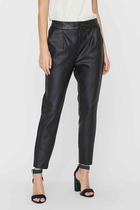 Zwarte lederlook broek van VERO MODA® met hoge taille, trekkoord en plooien, gedragen met hakken.