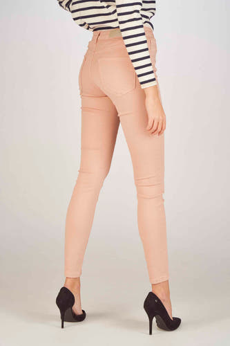 Jean skinny rose de VERO MODA, avec des talons noirs et un pull rayé.