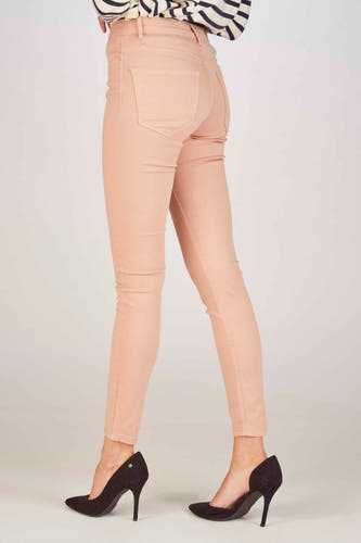 Jean skinny rose de VERO MODA, associé à des escarpins noirs et une chemise rayée.