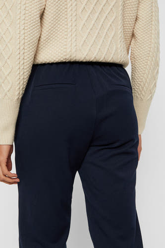 Pantalon de costume bleu VERO MODA, avec une partie arrière visible, associé à un pull crème avec un motif côtelé.