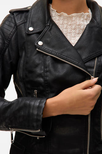 Manteau en cuir noir de Vero Moda, avec une fermeture éclair et des boutons argentés, porté sur un haut en dentelle.