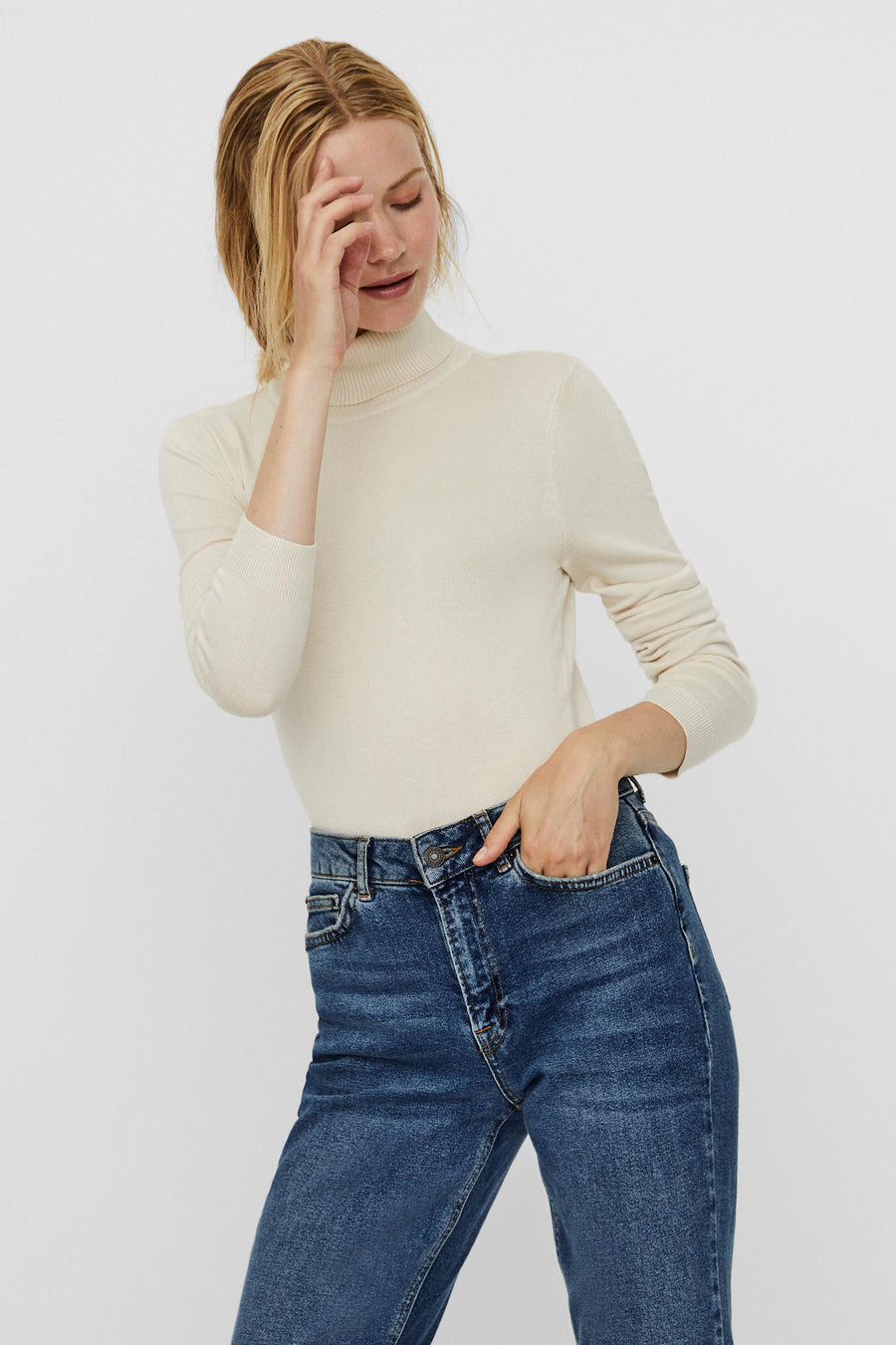Manteau beige de VERO MODA, porté avec des jeans bleus foncés et une main dans la poche.