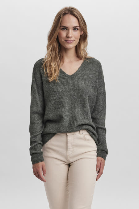 T-shirt vert de Vero MODA avec un col en V, porté avec un pantalon crème et des cheveux blonds décolorés.