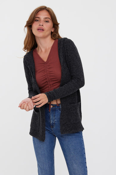Gilet noir de VERO MODA, avec capuchon, associé à un jean et des talons verts.