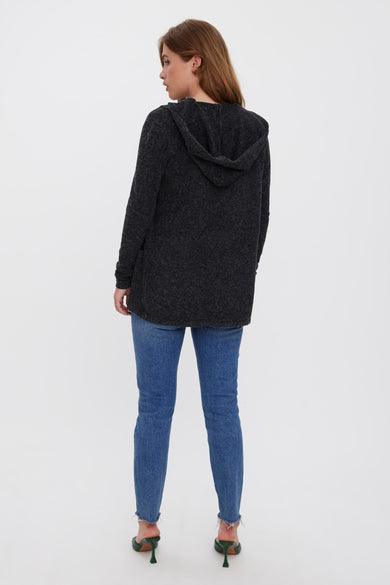 Zwarte vest van VERO MODA, met een capuchon, gecombineerd met jeans en groene hakken.
