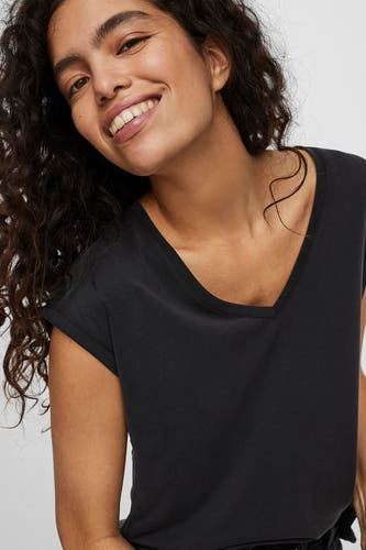 T-shirt noir à manches courtes de Vero Moda, gros plan d'une femme souriante aux cheveux bouclés.