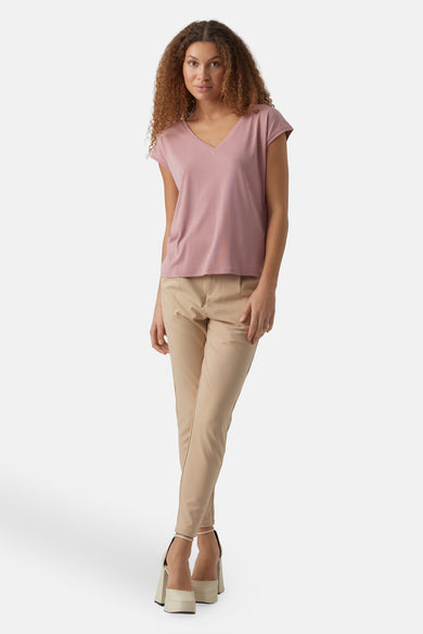 Roze T-shirt met korte mouwen van VERO MODA, gecombineerd met beige broek en witte hakken.