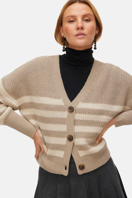 Beige cardigan van VERO MODA met horizontale strepen en bruine knopen, gedragen over een zwarte coltrui.
