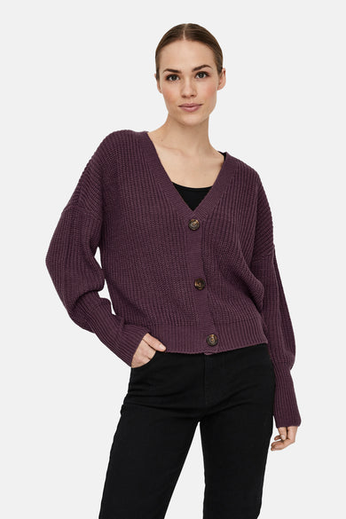 Paarse cardigan van VERO MODA met knoopsluiting en lange mouwen, gedragen over een zwarte top en broek.
