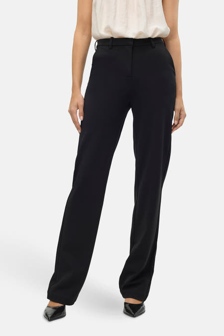 Zwarte kostuumbroek van VERO MODA, gecombineerd met een witte top en zwarte puntige hakken.